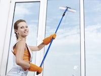 a woman cleaning a window with a roller