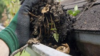 a person cleaning a gutter with a glove