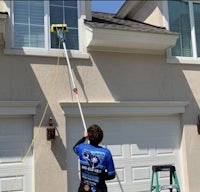 a man using a ladder to clean the windows of a house